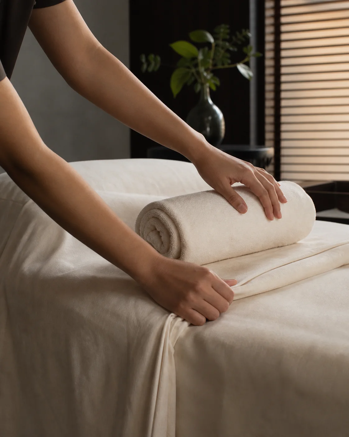 A spa professional preparing fresh linen in a treatment room