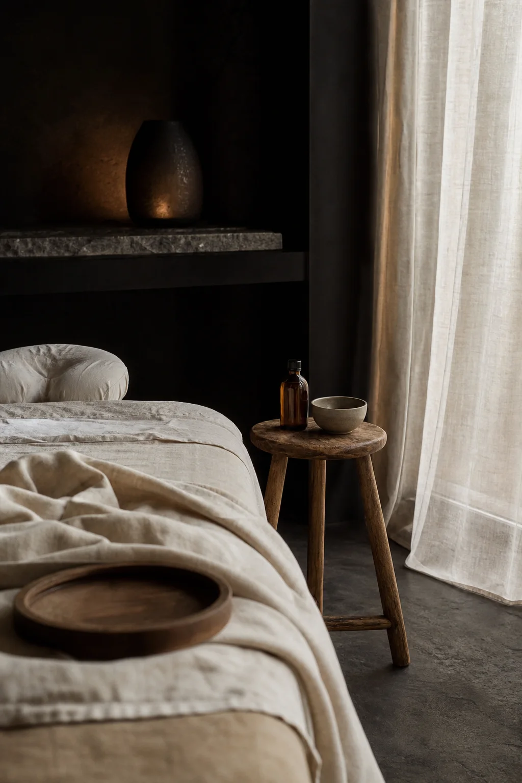 A massage table prepared beside an amber oil bottle and ceramic bowl