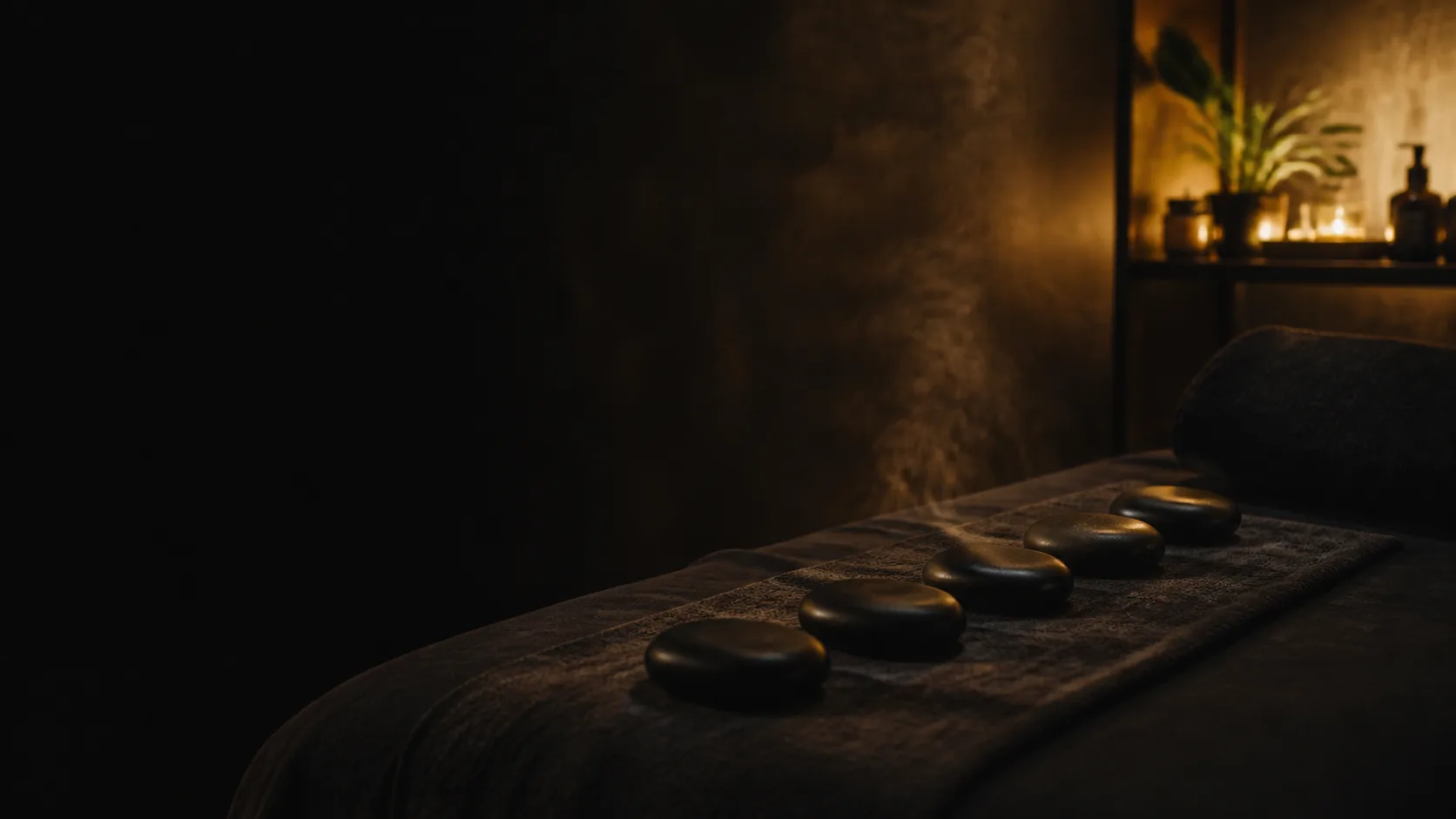 Heated basalt stones arranged beside a massage bed